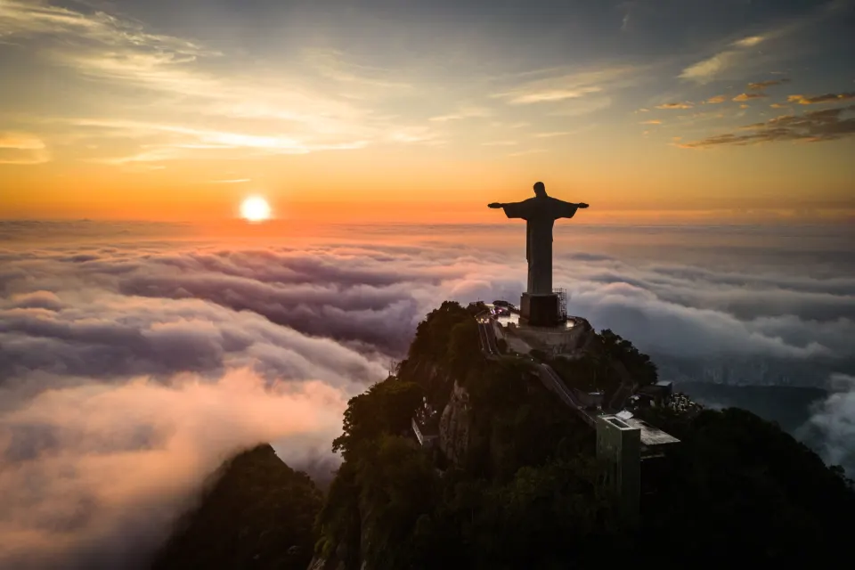 Christ the Redeemer statue on Corcovado silhouetted at sunrise above a sea of clouds