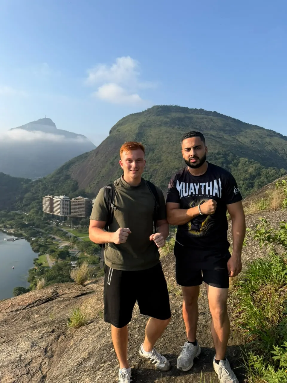 Two hikers on the Dois Irmãos trail with the lagoon and Pedra da Gávea behind