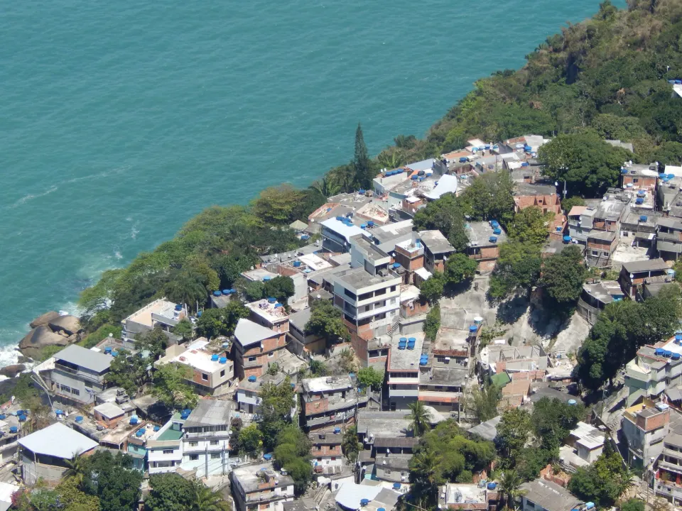 Rooftops of Vidigal favela with blue water tanks above the turquoise Atlantic Ocean