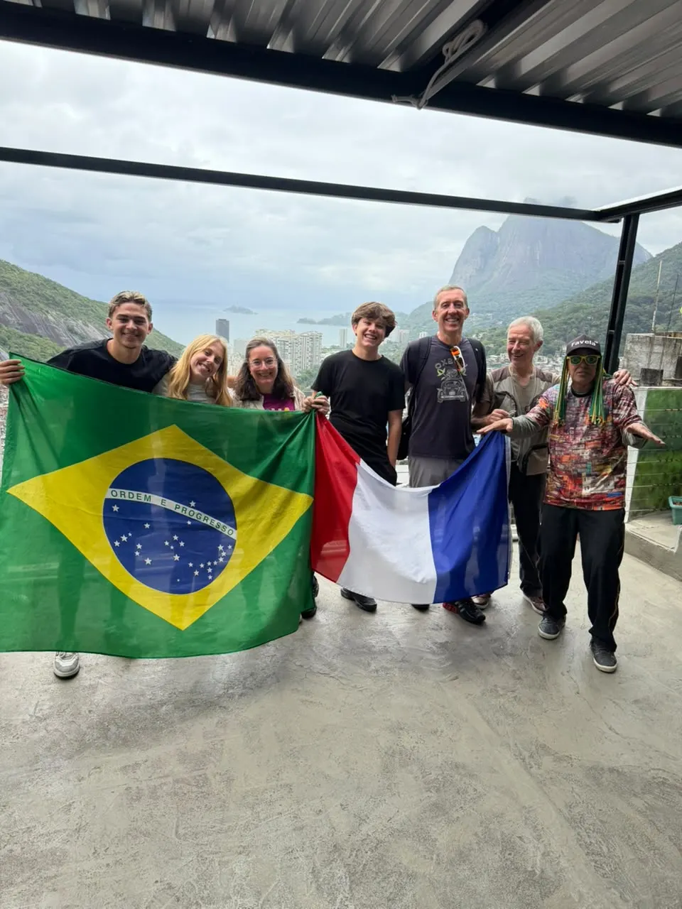 Guests with Brazilian and French flags on a favela rooftop viewpoint in Rio de Janeiro