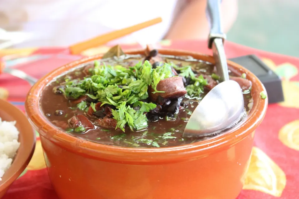 Clay pot of Brazilian feijoada black bean stew topped with fresh parsley