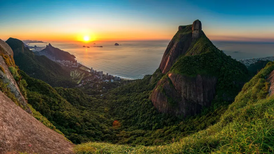 Sunrise over the Atlantic from a forested ridge facing Pedra da Gávea and São Conrado