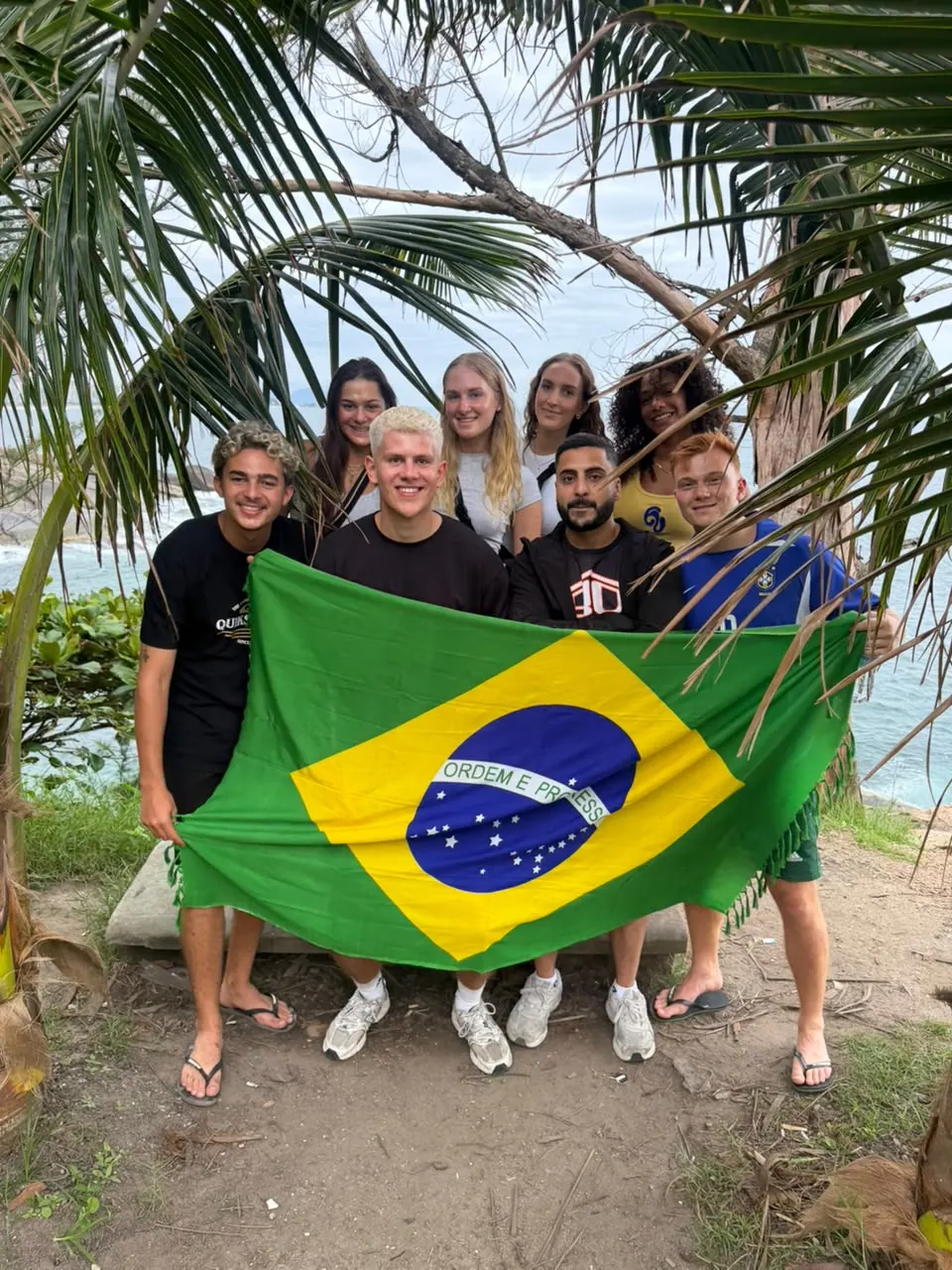 Travellers in Brazil football shirts on a summit at sunrise above the clouds